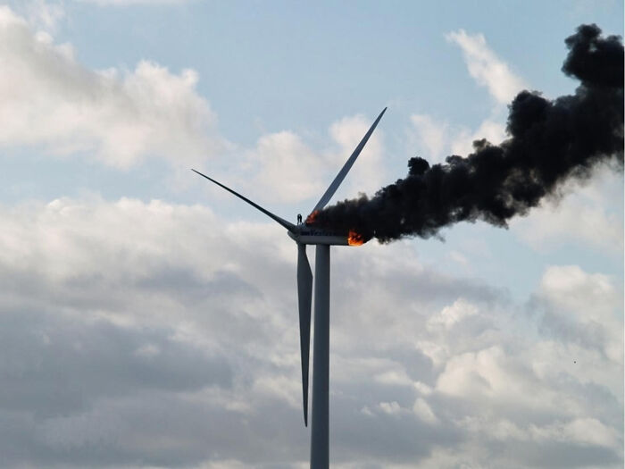Wind turbine on fire with thick black smoke rising on cloudy day in creepy photos