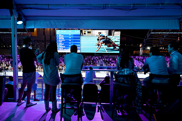 Audience watching running race on big screen at Steroid Olympics