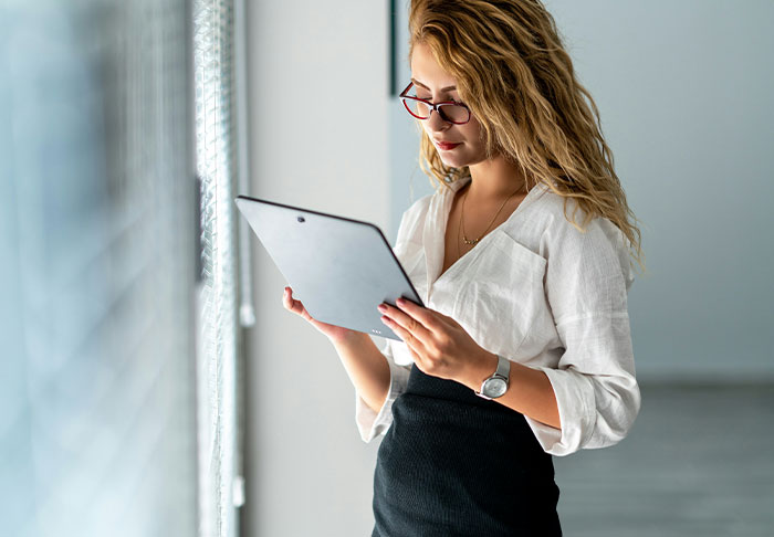 Young woman reading on digital tablet in office with focus on tablet Young woman reading on digital tablet in office with focus on tablet