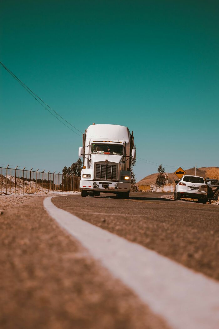 White semi truck driving on a desert highway under clear sky