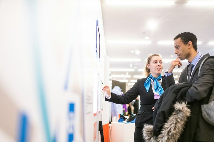 Airport employee explaining information to traveler at booth
