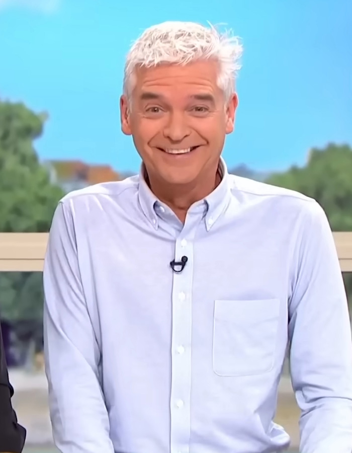 Smiling man with gray hair in white shirt hosting a show about dramatic coming out stories