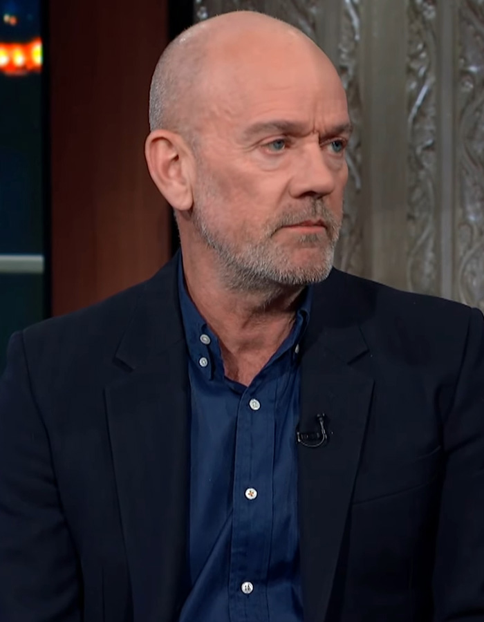 Bald man with a beard wearing a suit appearing serious during an interview on coming out gay