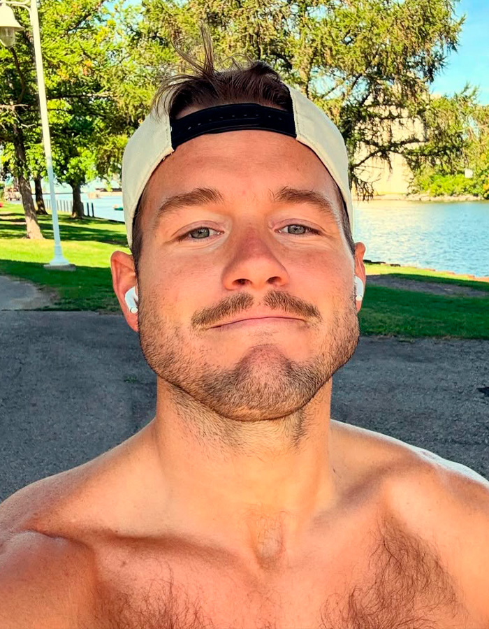 Close-up of a shirtless man wearing a cap with a background of trees and water, representing coming out gay stories