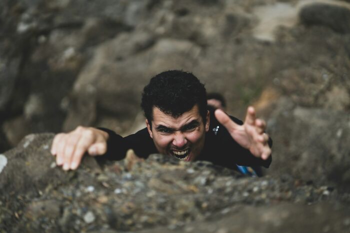 Man climbing rocky surface showing intense expression random facts