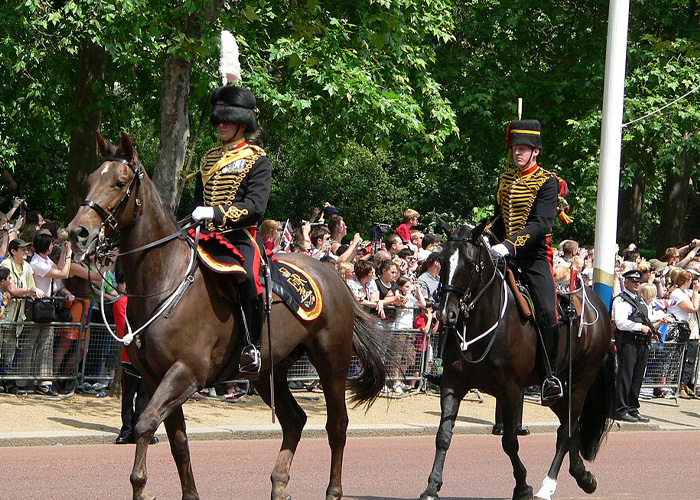 Military horse riders in ceremonial uniform with crowd behind barriers Military horse riders in ceremonial uniform with crowd behind barriers