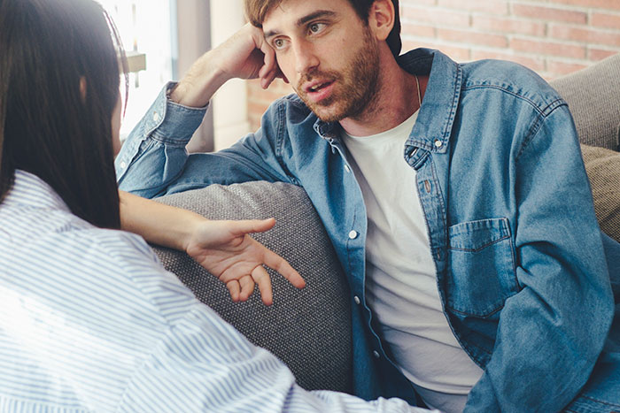 Man in a denim shirt talking to his fianc&eacute;e about manipulative parents, trying to decide what to do.