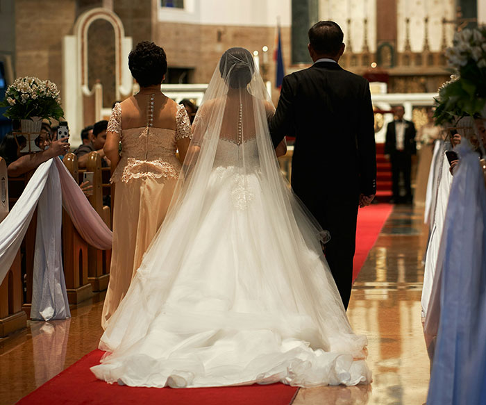 Bride walking down the aisle with late husband's parents in wedding ceremony