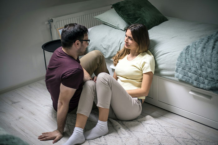 Couple discussing wedding plans sitting on bedroom floor