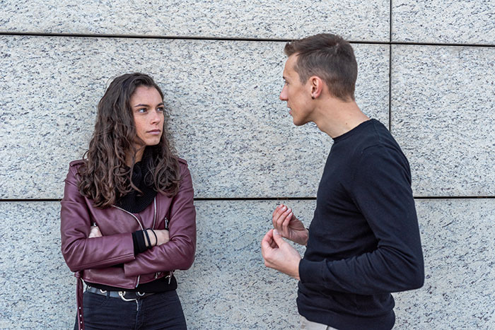 A woman with curly hair looking away from a man talking, illustrating first date cringe-worthy stories.