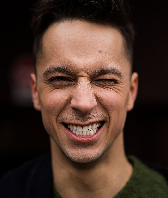 A man with a wide, cringe-worthy smile and squinting eyes, possibly from a scary first date story.
