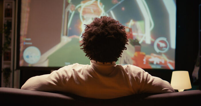 Person watching a video game on a large screen from behind on couch