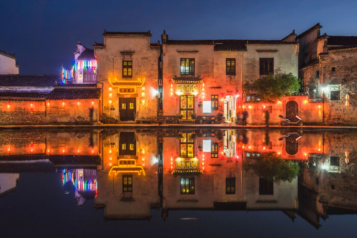 Night view of illuminated buildings reflecting on water surface
