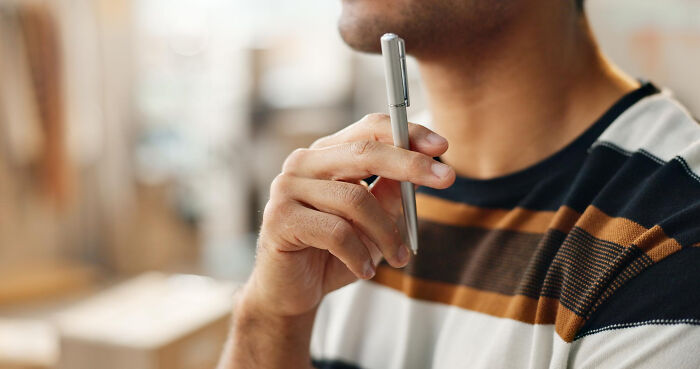 Man thoughtfully holding pen, considering pizza delivery driver stories
