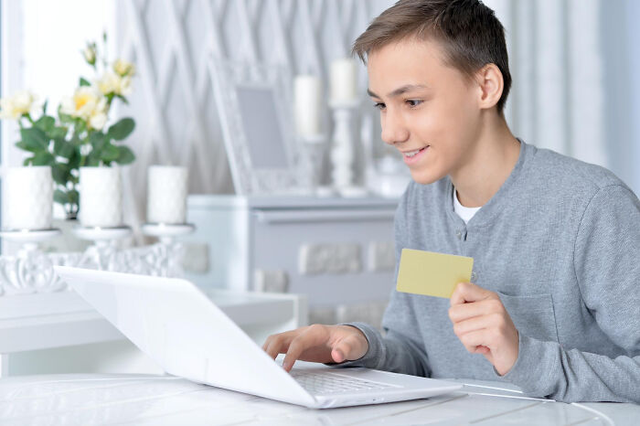 Young man shopping online holding credit card with laptop
