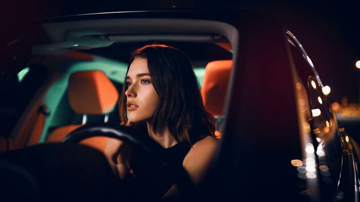 Young woman looking thoughtfully while sitting in car at night