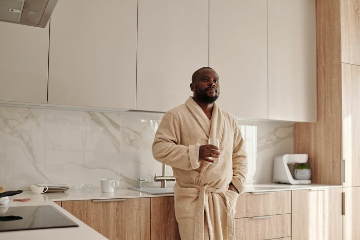 Man in bathrobe drinking coffee in modern kitchen