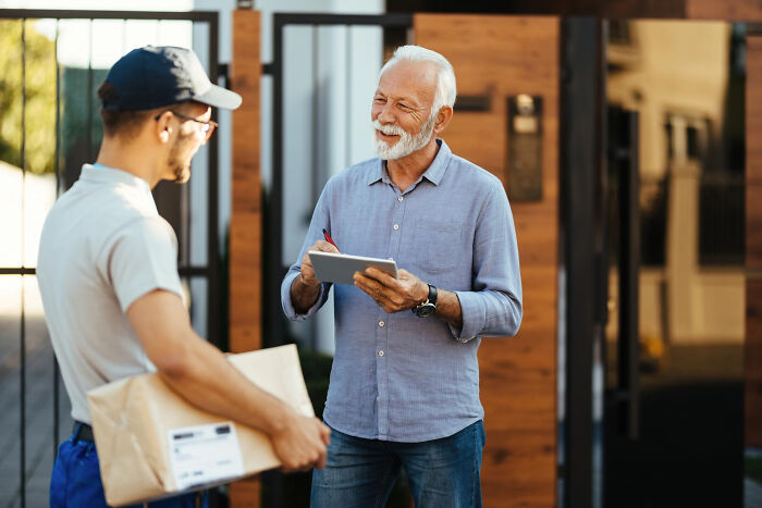 Pizza delivery driver handing package to happy customer outside home