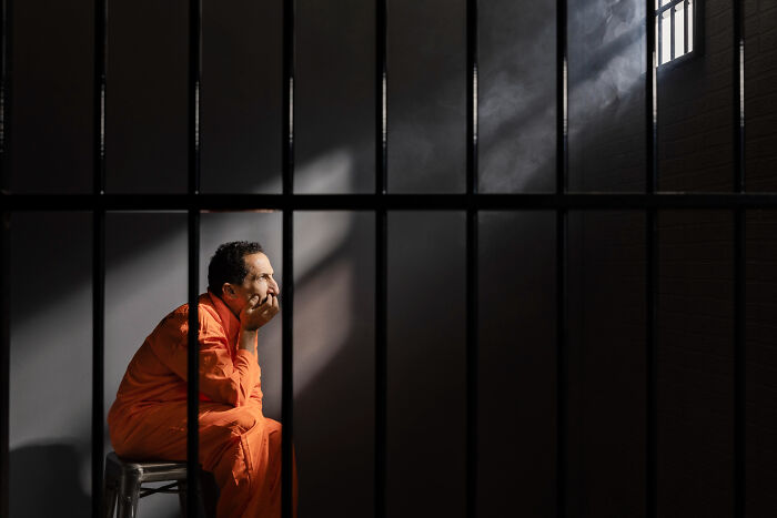 Man in prison wearing orange jumpsuit, symbolizing banned pizza delivery customers