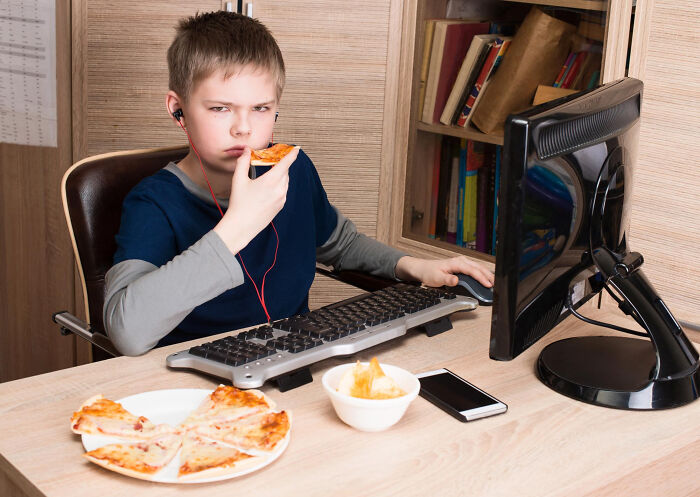 Boy eating pizza while using computer at home, related to pizza delivery drivers stories