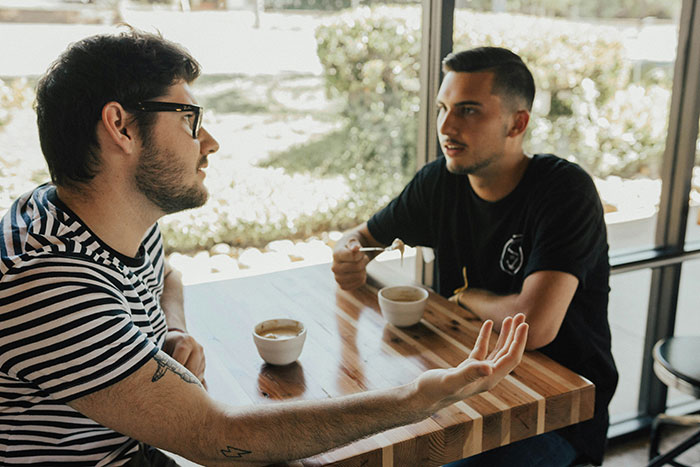 Two men having a serious conversation over coffee at a table Two men having a serious conversation over coffee at a table