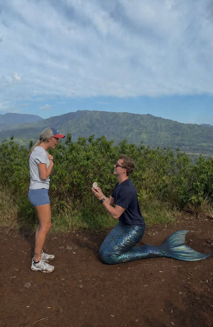 A man in a mermaid tail proposes to a woman on a mountain, creating a viral proposal pic.