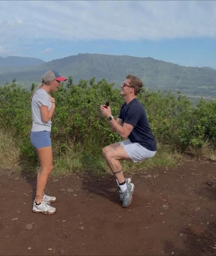 Man proposing to a woman outdoors with mountains in the background, inspiring hilarious edits.