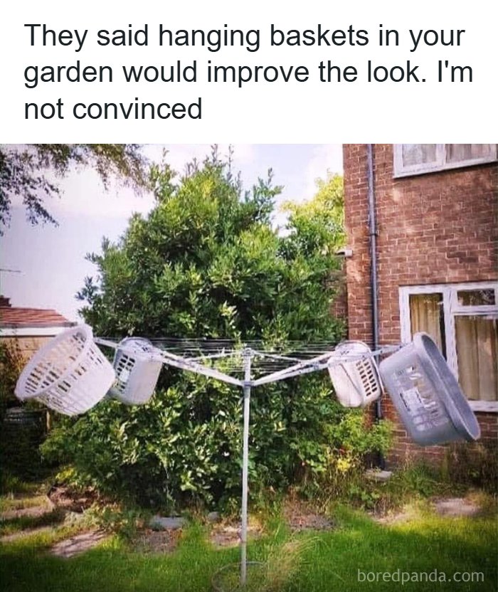 Four laundry baskets hanging on a rotary clothesline in a garden, creating a funny and random meme.