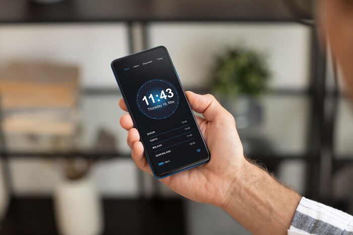 A person holding a smartphone displaying the current time and several world clocks. Wild encounters with technology.
