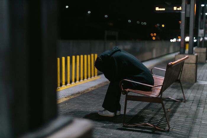 Person sitting alone on bench at night feeling down