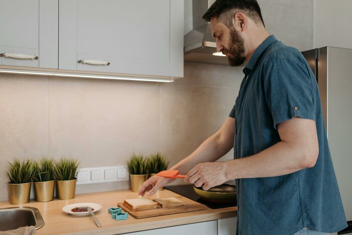 Man preparing sandwich in kitchen with cooking utensils