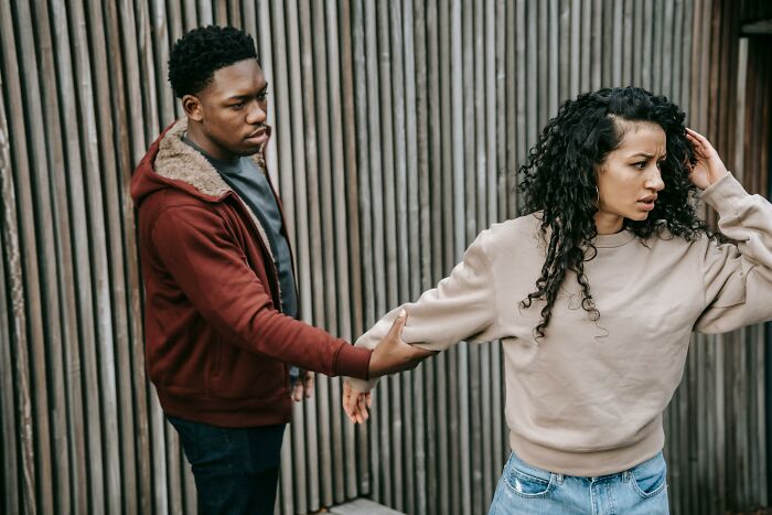 Man holding woman’s arm while she pulls away upset