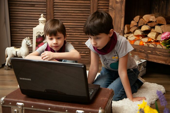 Two children focused on laptop screen indoors near fireplace, representing sharp comebacks context