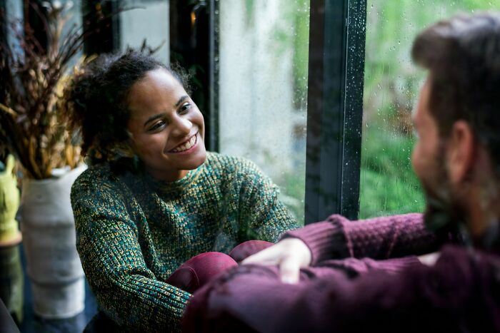 Smiling woman and man talking near window in casual setting