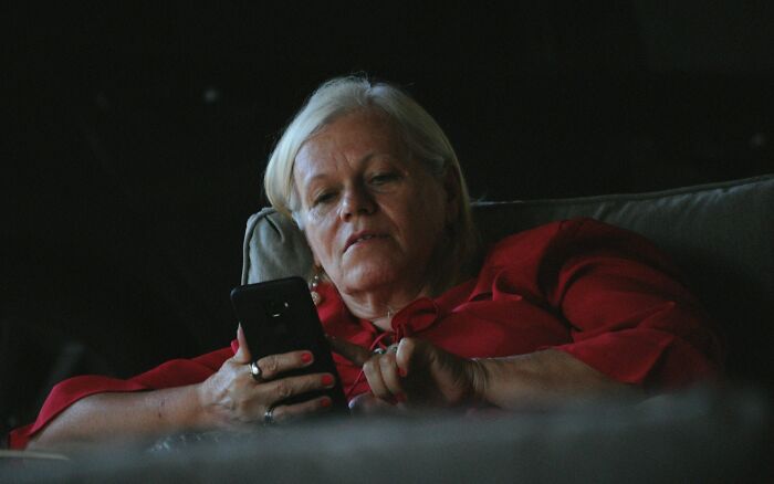 Woman in red shirt looking at smartphone thoughtfully