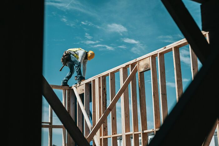 Construction worker framing wooden structure outdoors with blue sky, metaphor for sharp comebacks building