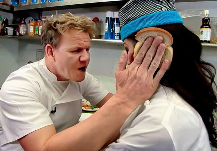 Chef holding bread to another person’s face in kitchen, depicting sharp comebacks related to sandwich