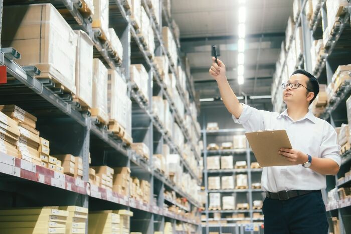 Warehouse worker inspecting shelves and inventory with clipboard