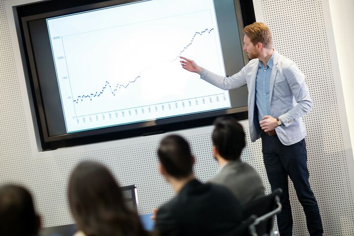 Economist explaining financial data on screen to an audience
