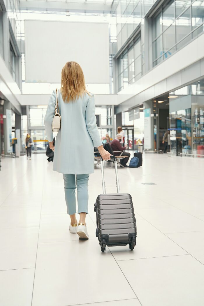 Woman walking with rolling suitcase in bright airport terminal