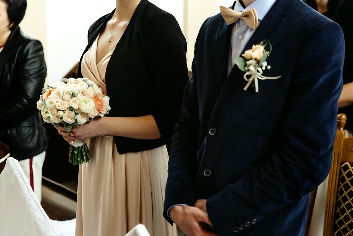 Wedding guests holding bouquet and wearing formal attire at ceremony