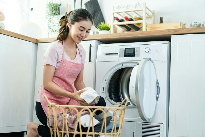 Woman doing laundry with distracted expression showing brain on auto pilot error
