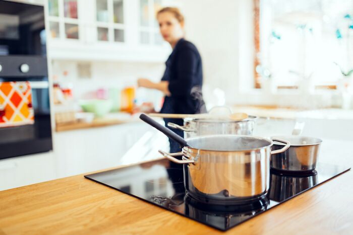Cooking pots boiling on stovetop with blurred woman in background