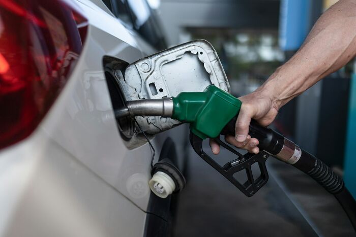 Person fueling car at gas station illustrating inevitable fuel dependency