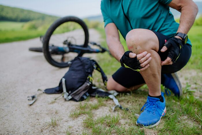 A man with a scraped knee after falling off his bike, highlighting potential health warning signs beyond just injuries. Routine Cancer Screening.