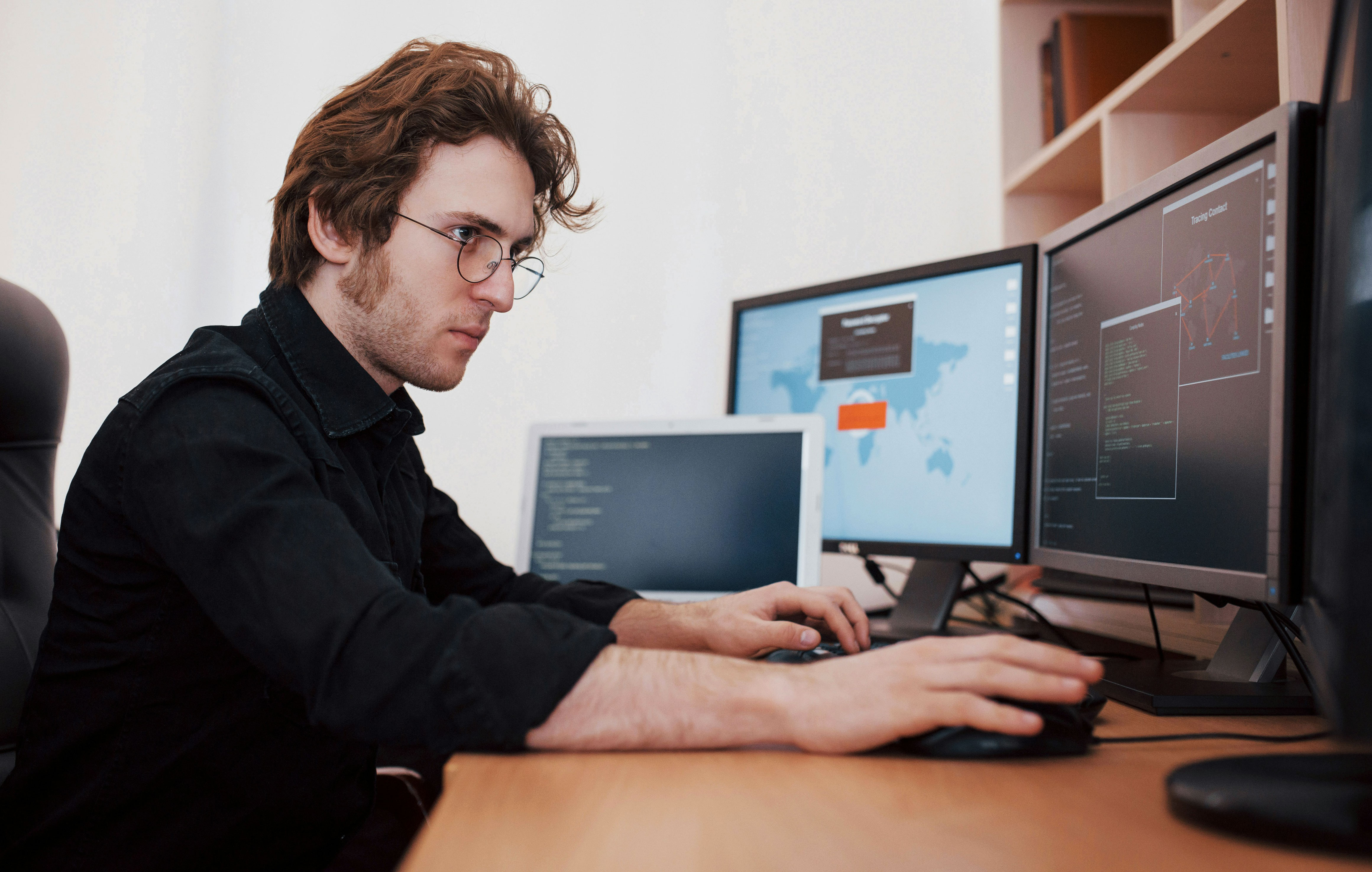 Engineer focused on coding automation script at multiple computer monitors