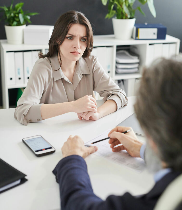 A young woman with a concerned expression talking to a lawyer, discussing hard cases. She looks stressed.