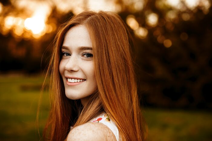 Portrait of smiling red-haired woman outdoors in sunset