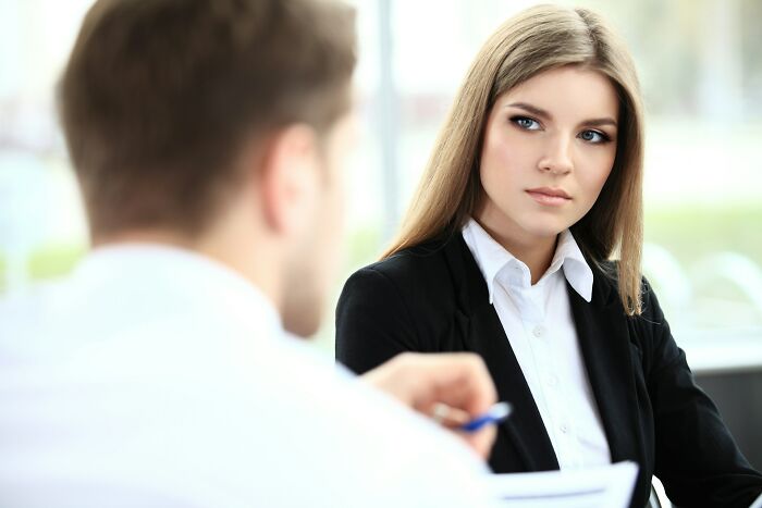 A serious young woman in a black blazer and white shirt listening intently. She's ready with epic comebacks.