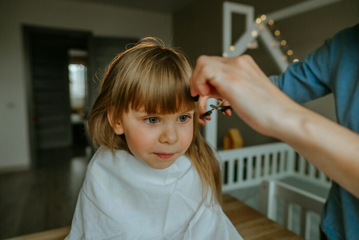 Child getting a haircut indoors with focus on the haircut process